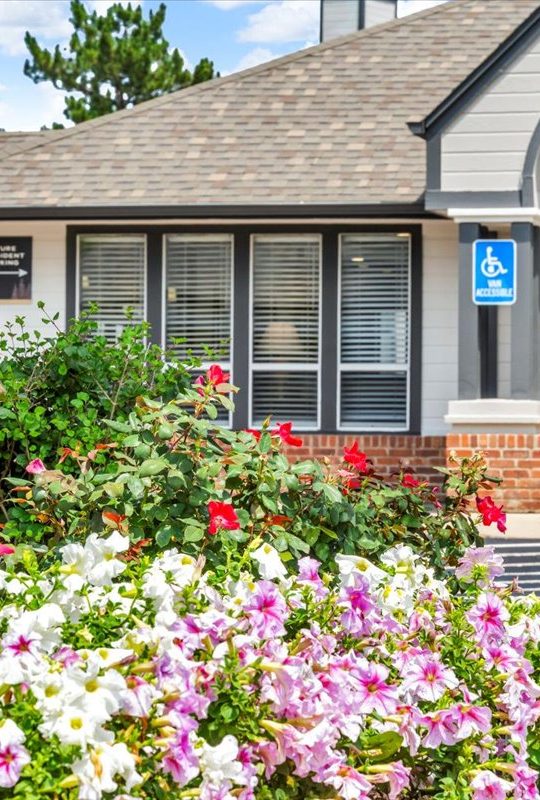 a building with flowers and bushes in front of it at The Residences at Bear Creek