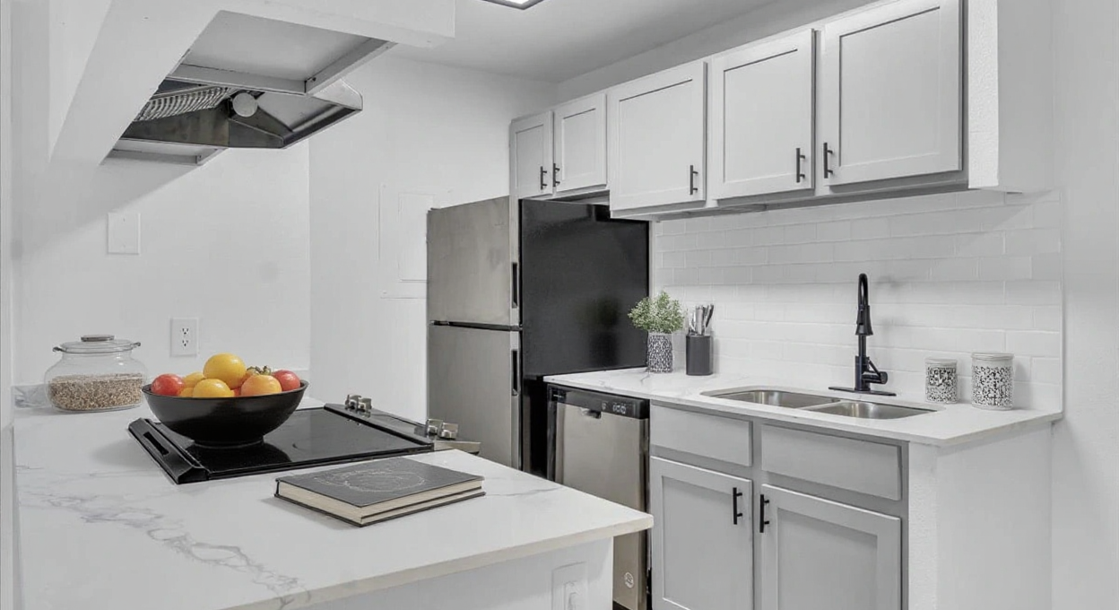 a white kitchen with stainless steel appliances and a sink at The Residences at Bear Creek